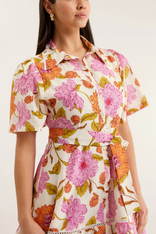 Woman wearing a floral dress with pink and orange flowers on a white background
