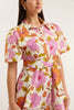 Woman wearing a floral dress with pink and orange flowers on a white background