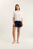 Woman wearing a white shirt and navy shorts on a white background