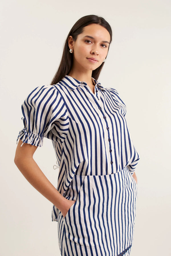 Woman wearing a blue and white striped dress against a plain background