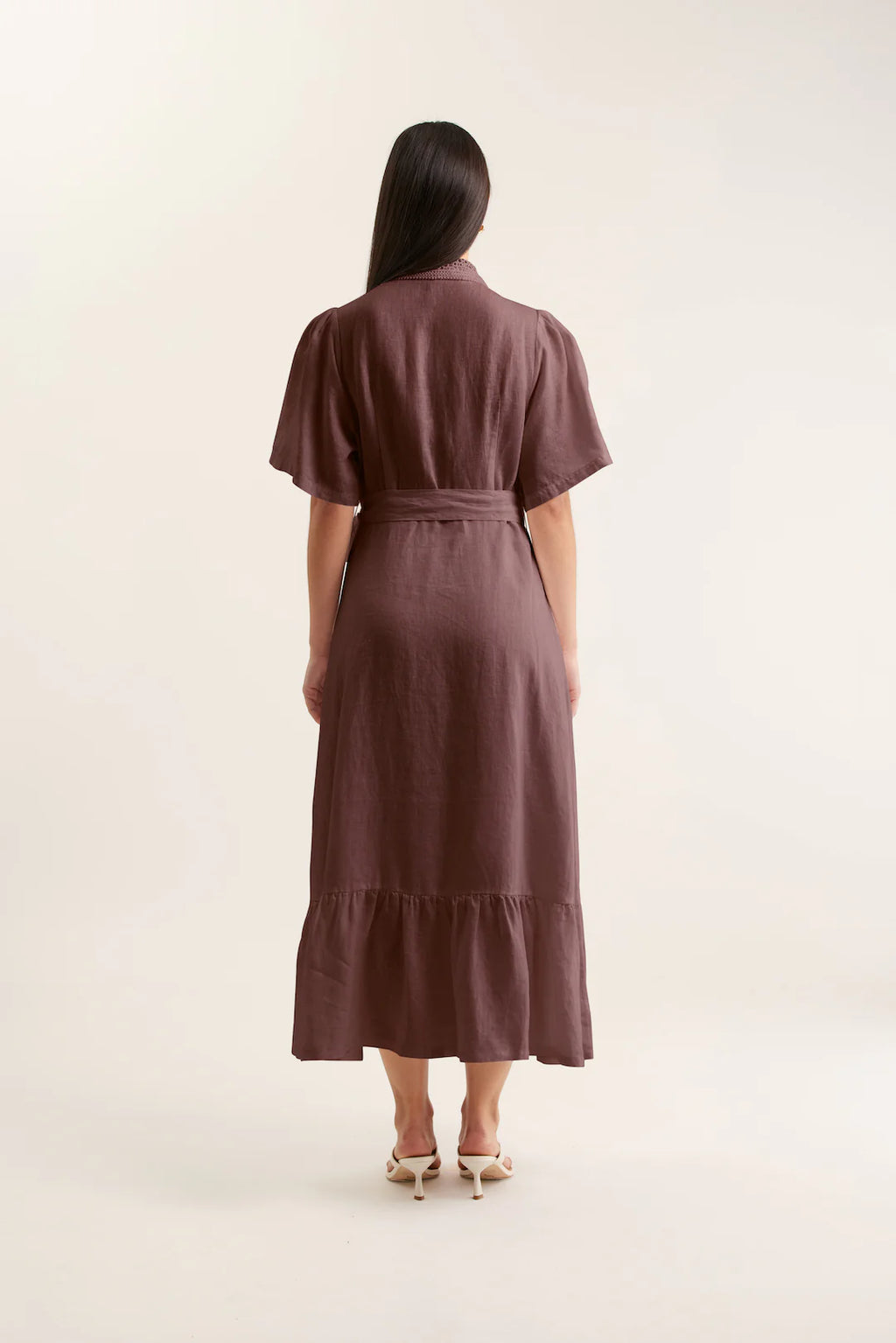 Woman wearing a brown dress with a belt on a white background