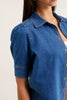 Blue denim shirt worn by a person on a plain background