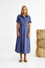 Woman wearing a blue dress standing next to hay bales on a white background
