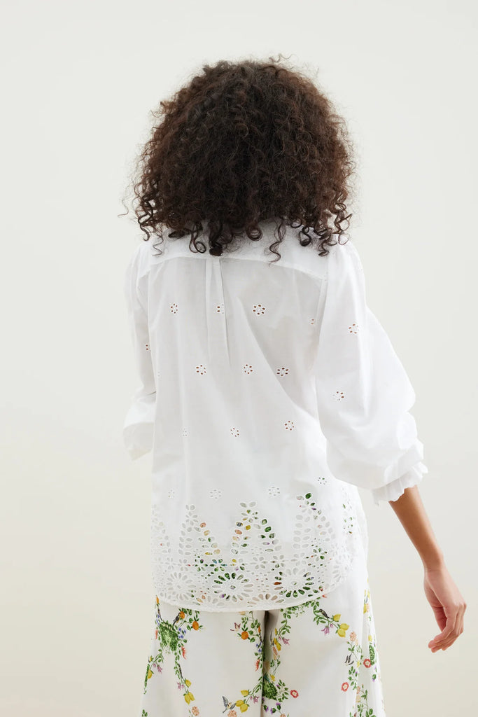 The Zicatela Shirt from Binny is a lightweight white cotton voile shirt with intricate hem embroidery, gently shirred sleeves and sweetly ruffled lapel. 