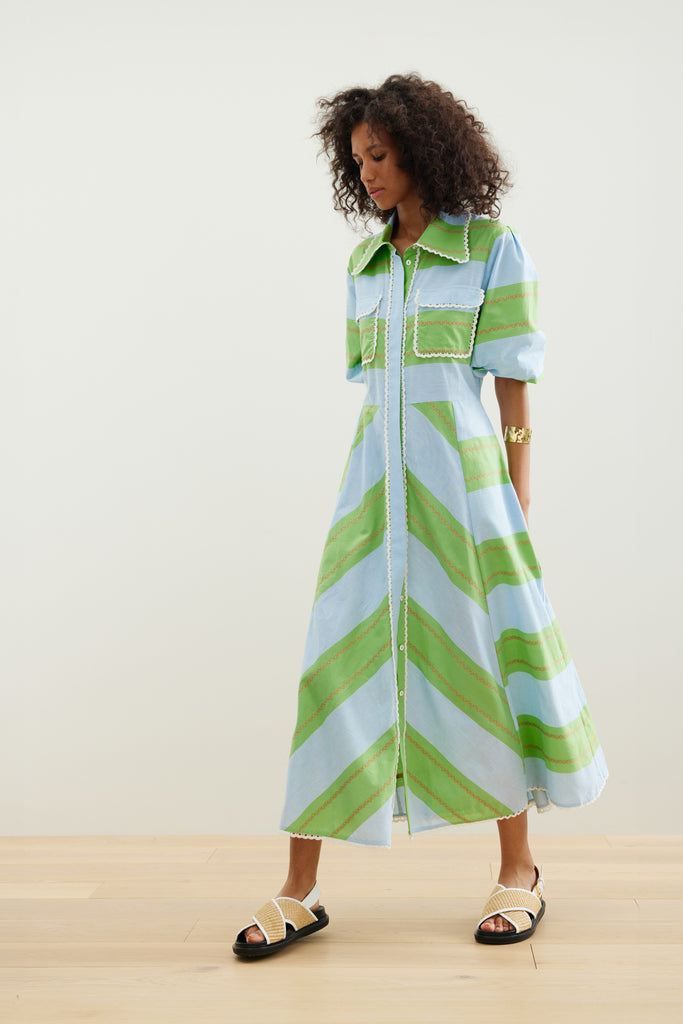 The Legend of San Blas Dress from Binny features yarn dye sky blue and grass green cotton poplin stripes with a tiny wiggle of orange, finished with cotton crochet lace trim.