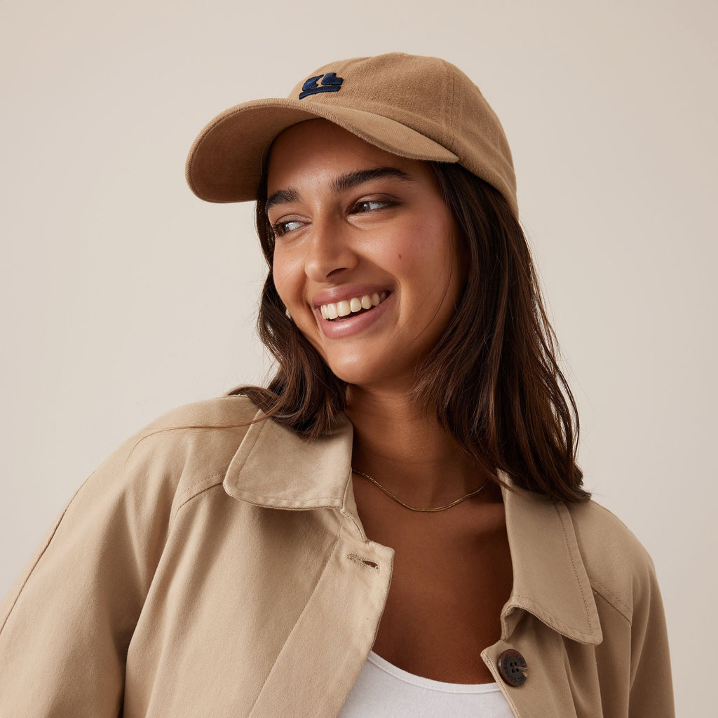 Woman wearing a beige cap and coat with a plain background