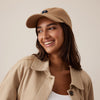 Woman wearing a beige cap and coat with a plain background