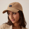 Woman wearing a beige cap and jacket with a neutral background