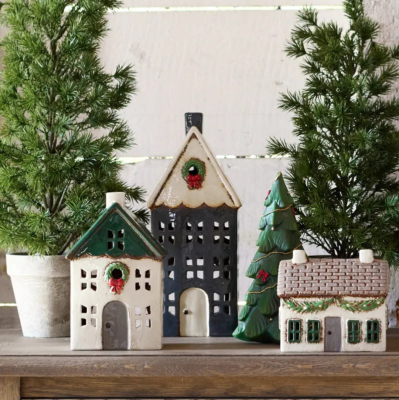 Decorative ceramic houses with Christmas trees on a wooden surface