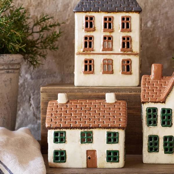 Set of ceramic house-shaped containers on a wooden surface with a neutral background.