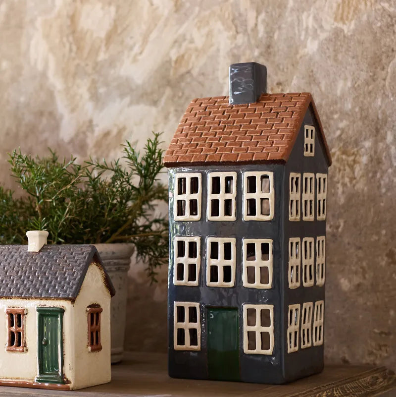 Decorative ceramic house models on a wooden surface with a stone wall background