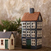 Decorative ceramic house models on a wooden surface with a stone wall background