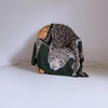 Green jacket with leopard print pattern draped over a chair against a plain background