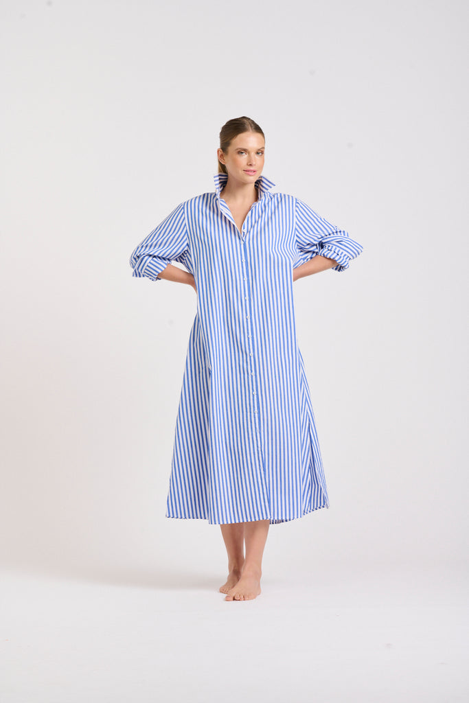 Girl wearing a long sleeve shirt dress that is midi length.  The colour is blue and white stripe and designer is Shirty