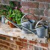 two sophie conran for burgon & Ball silver galvanised watering cans in a garden setting