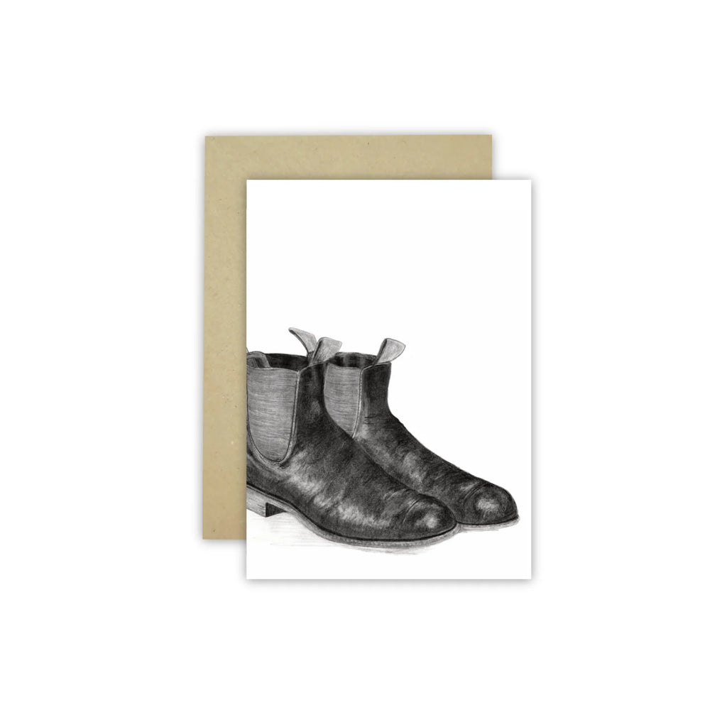 White gift card with black pencil drawing of the muzzle of riding boots alongside a kraft envelope. Drawn by australian artist Cathy Hamilton.