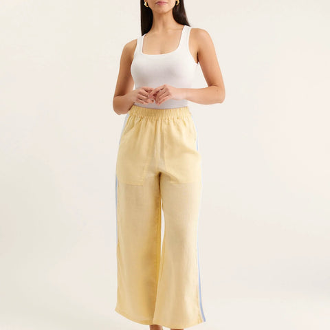Woman wearing a white tank top and yellow pants with a white background