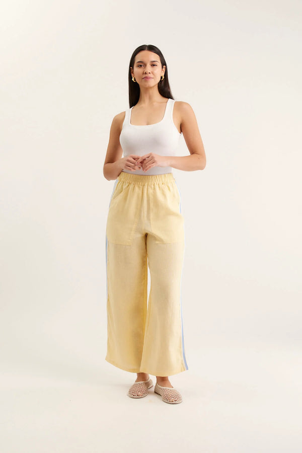 Woman wearing a white tank top and yellow pants with a white background