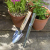 A Burgon and Ball cell tray trowel and a seedling widger leaning against a terracotta pot plant